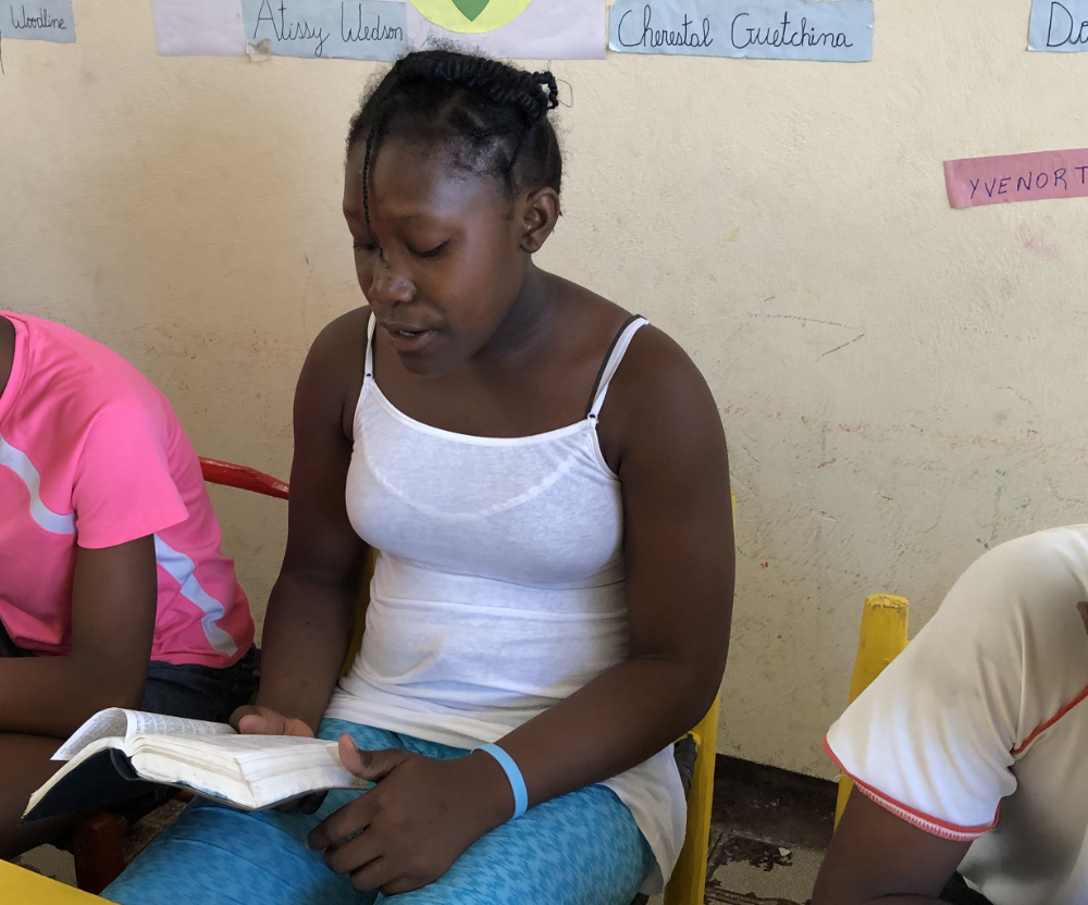 student Saintilus Angeline reading a bible in classroom