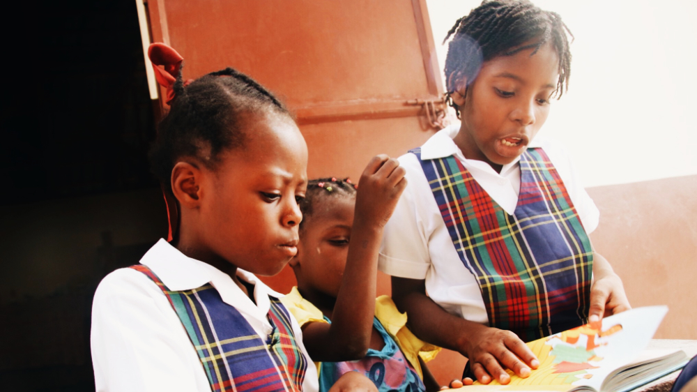 connect 2 ministries children reading a book in Haiti compound