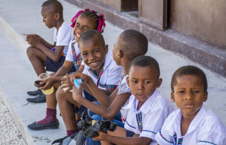 Haitian children in school uniforms eating snacks on curbside
