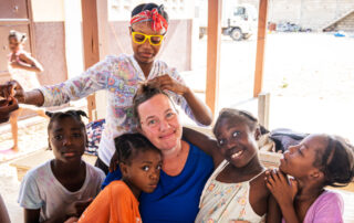 Happy woman having her hair braided and surrounded by happy children