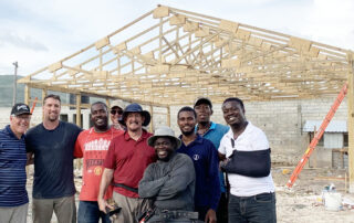 Construction volunteers pose for picture with pastors and project building in background.