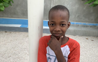 Haitian boy smiling with his hand on his chin