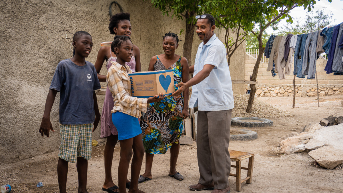 Haitian family of 4 being gifted a food pak by a Pastor