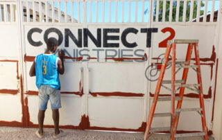 boy painting a connect 2 ministries gate in Haiti