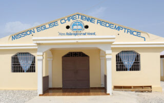 The front view of yellow single level Haitian church.