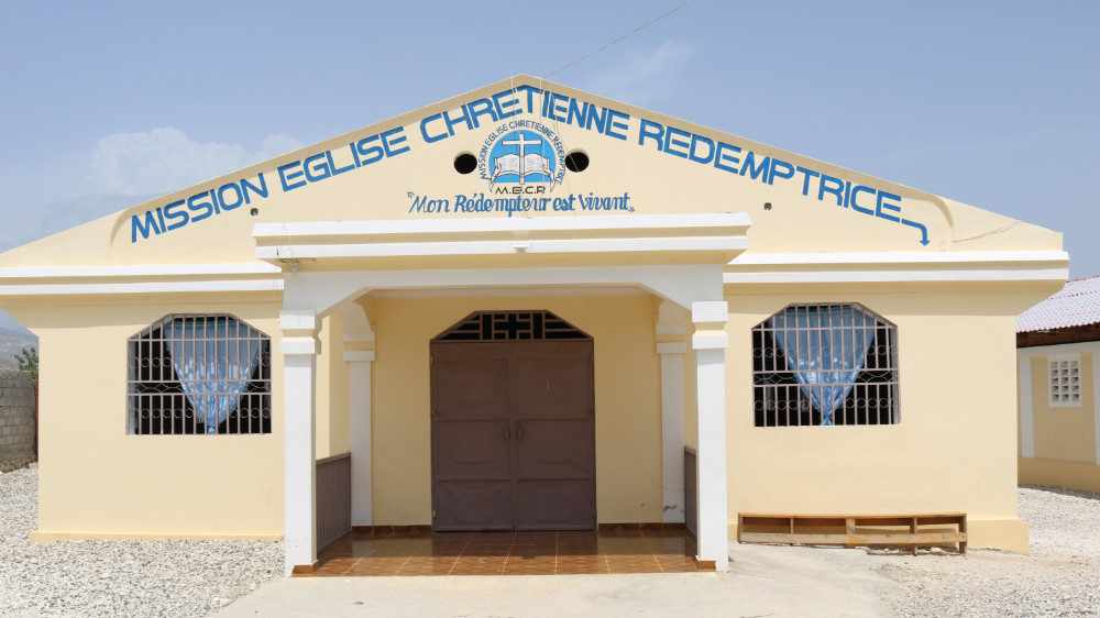 The front view of yellow single level Haitian church.