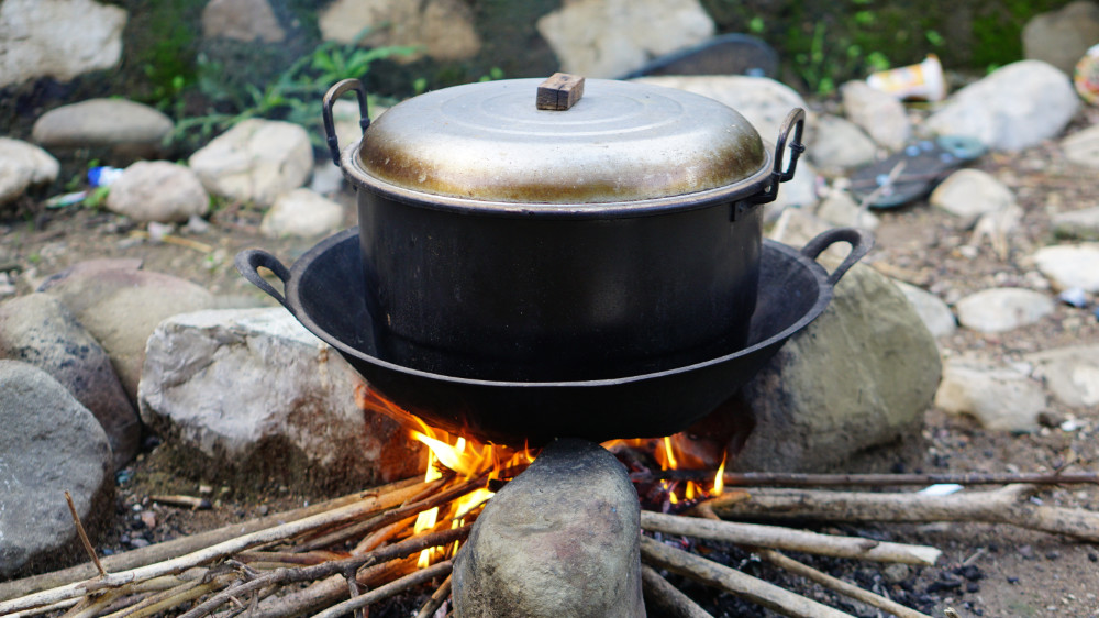 A pot on top of three stones and an outdoor fire, Haitian method of cooking.