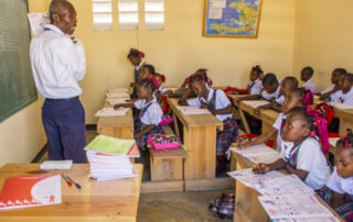 Teacher and grade school students in classroom in Haiti.