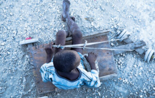 Ariel view of Haitian street child on a wooden cart, on a gravel path
