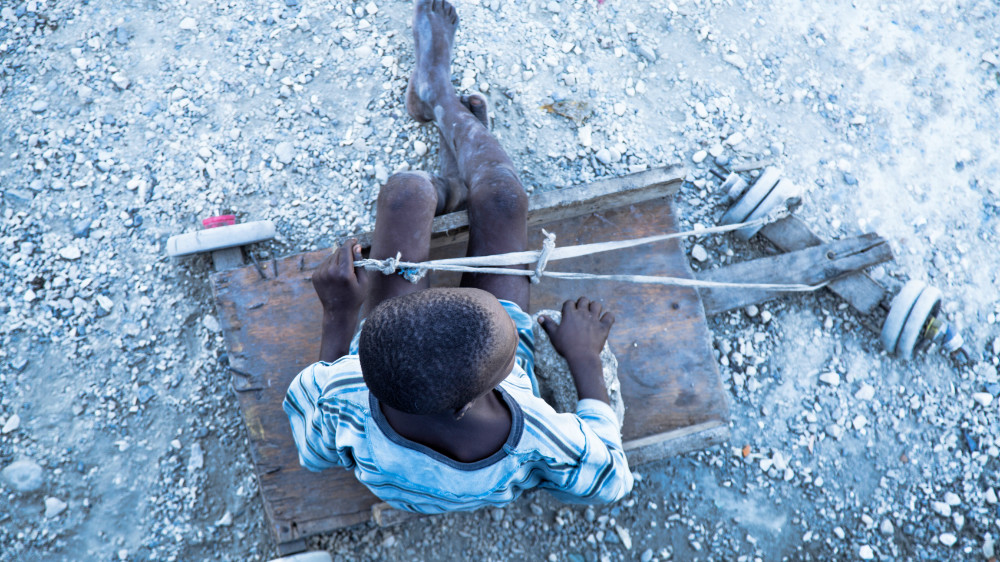 Ariel view of Haitian street child on a wooden cart, on a gravel path