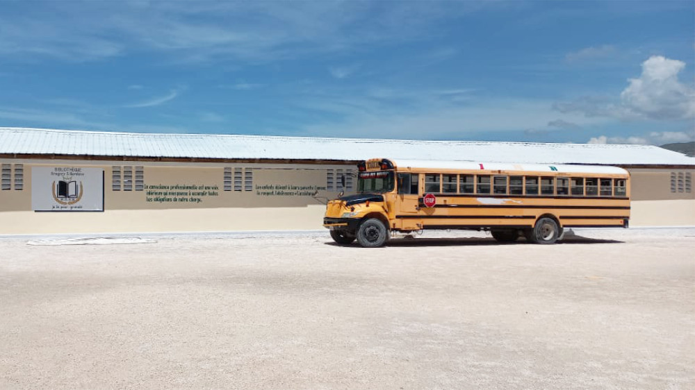 School Bus on a dirt lot in front of a church in Haiti.
