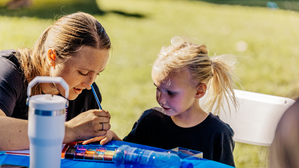 Volunteers face painting in park.