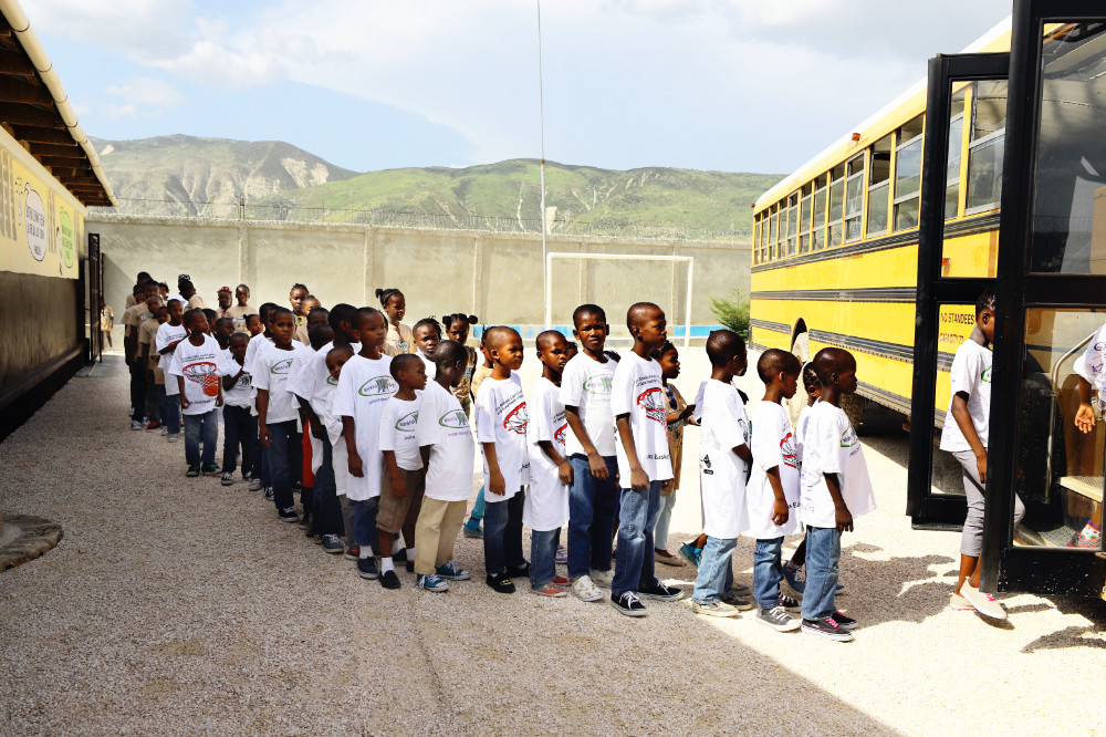 Haitian children in line to board a school bus.