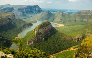 Ariel view of lush valley landscape with river and mountains.