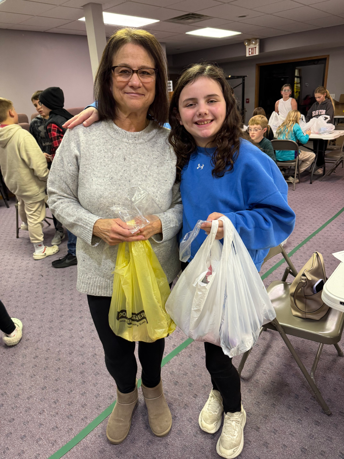 Two AWANA volunteers, a woman and young female child posing for a picture at the Christmas shoe box drive.