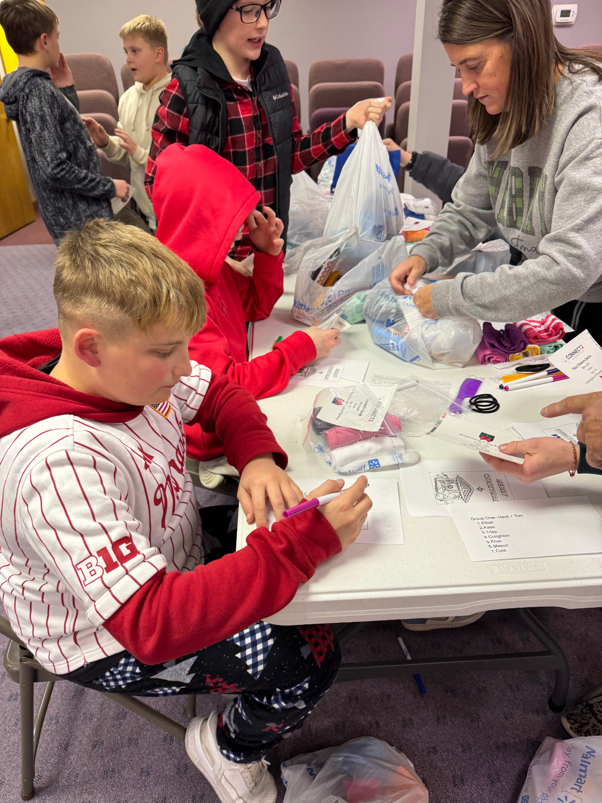 AWANA volunteers, adults and children at a table making cards for Christmas shoe box drive.