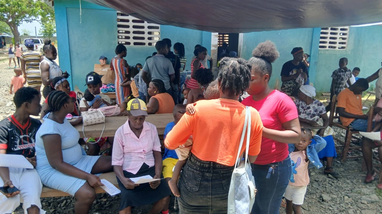 People gather under a shaded area